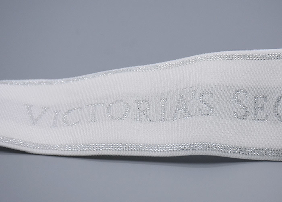 L'habillement a adapté la bande aux besoins du client élastique de jacquard blanc de 35mm avec le logo argenté brillant